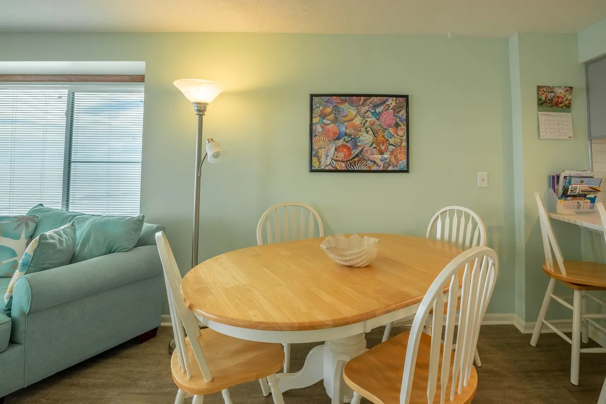 This image showcases a cozy dining area with a table set for four, a comfortable sofa nearby, and colorful artwork adorning the walls. The scene suggests a space ideal for family breakfasts, intimate dinners, and relaxed gatherings.
