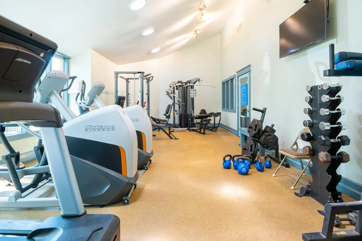 A modern fitness center equipped with treadmills, weight machines, kettlebells, and dumbbells. The room is designed for both cardio and strength training, motivating guests to maintain their fitness routines while on vacation.