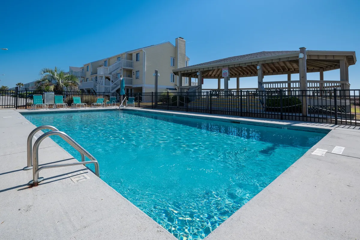 An inviting exterior pool area complete with a sparkling swimming pool, poolside lounge chairs, and a gazebo. The space is surrounded by lush greenery, offering a relaxing environment for sunbathing, swimming, or unwinding together.